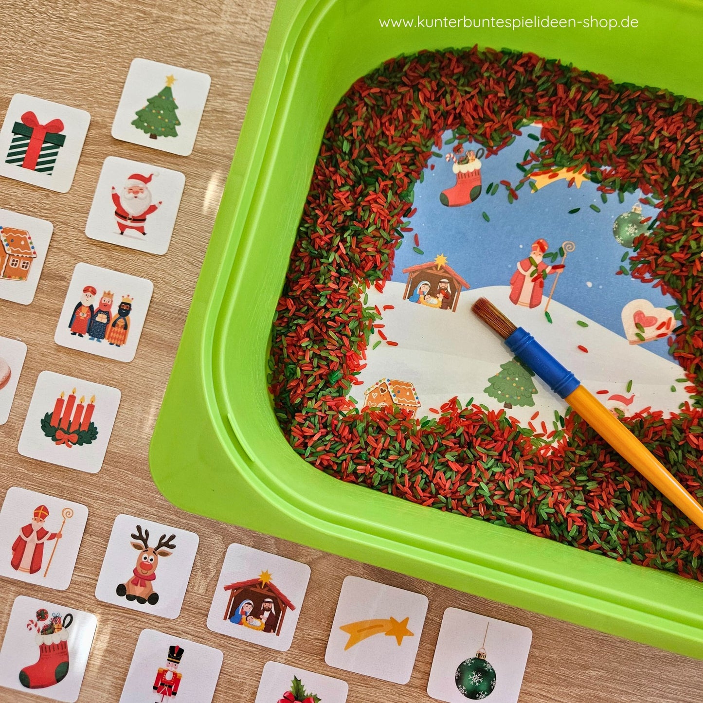 Montessori Aktionstablett mit Pinsel, Spielreis und Kartenraster: weihnachtliche Symbole (Geschenk, Sternschnuppe, Nikolaus, Krippe) laden zum Sensory Play ein – konzentriertes Finden, Sortieren und Benennen; praxistaugliches Kinderhaus-Material für Kita & Vorschule.