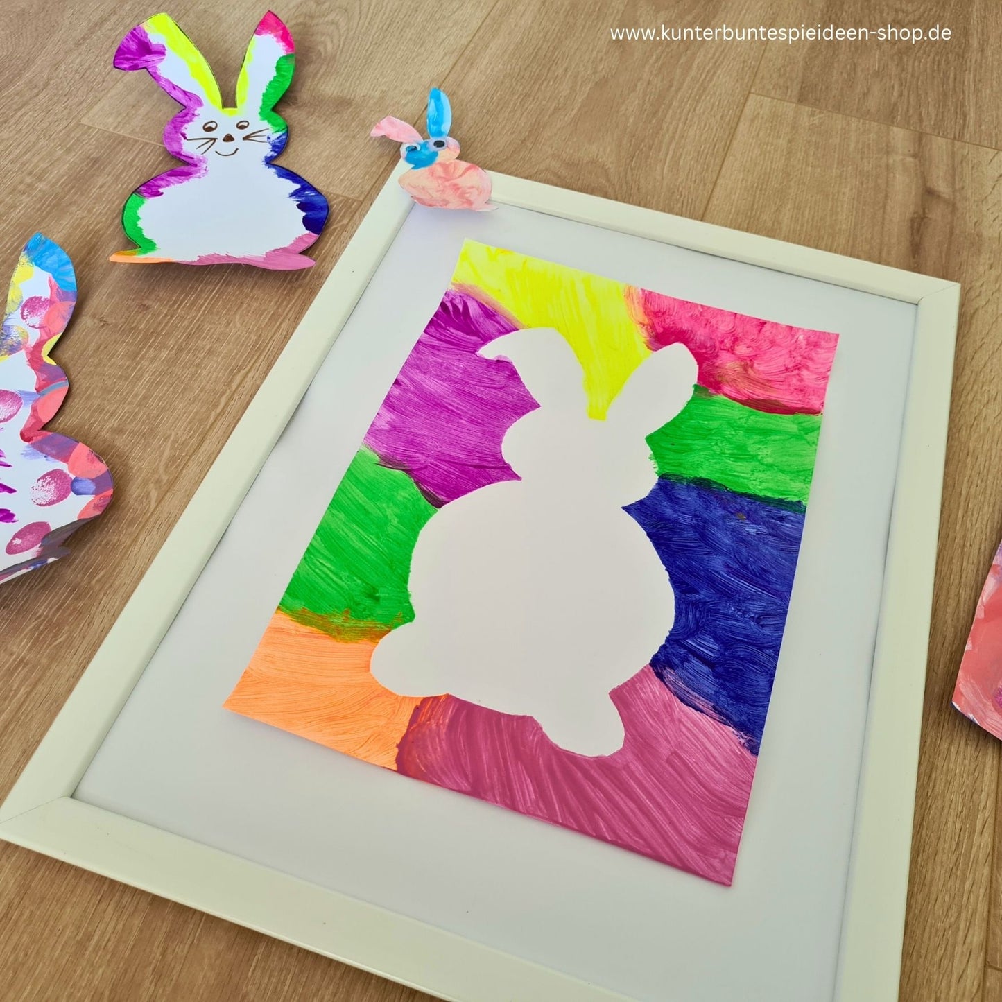 Fertiges Bastelbeispiel mit weißer Osterhasen-Silhouette vor leuchtend buntem Hintergrund. Die Osterhase Kontur Vorlage zum Ausdrucken eignet sich gut für Osterbasteln mit Kindern.