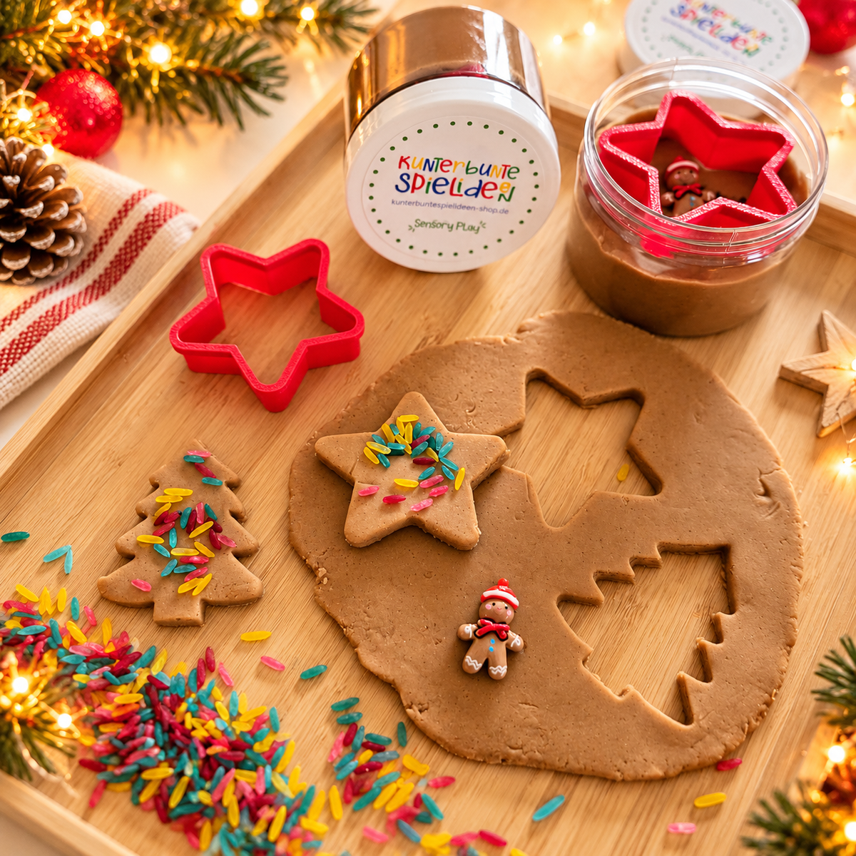 Weihnachtsbäckerei Knetset für Kinder mit brauner Knete in der Dose, rotem Stern-Ausstecher, bunten Reisstreuseln und Lebkuchenmännchen zum Plätzchenspielen.