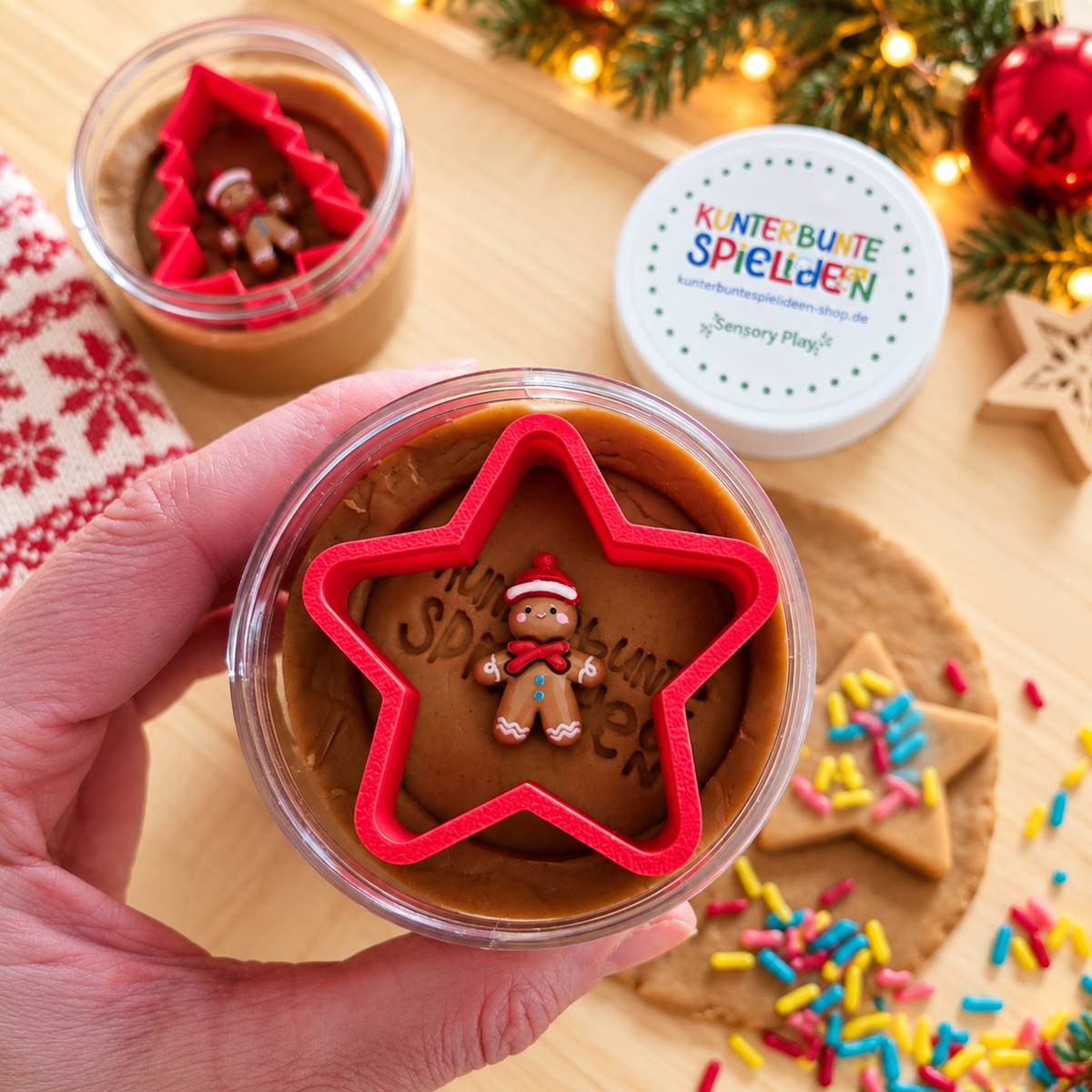 Plätzchen ausstechen mit Knete – braune Spielknete mit ausgestochenem Tannenbaum, rotem Plätzchenausstecher, verziertem Stern und Lebkuchenmännchen.