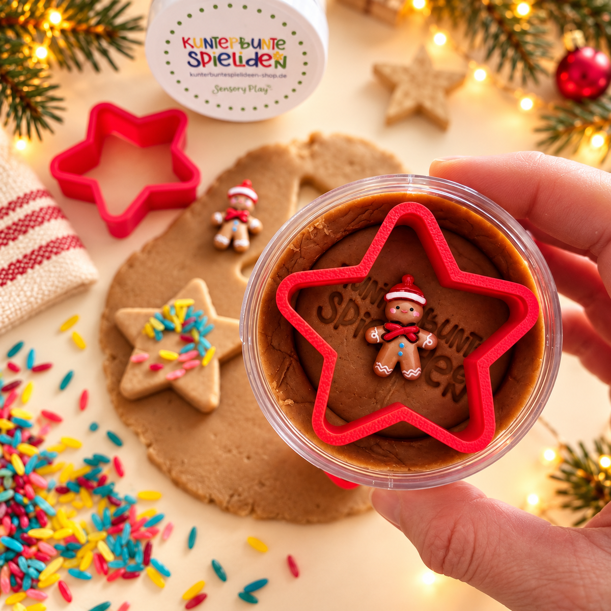 Knete in der Dose als kleine Weihnachtsgeschenkidee für Kinder – braune Spielknete mit rotem Stern-Ausstecher und Lebkuchenmännchen in einer Hand gehalten.