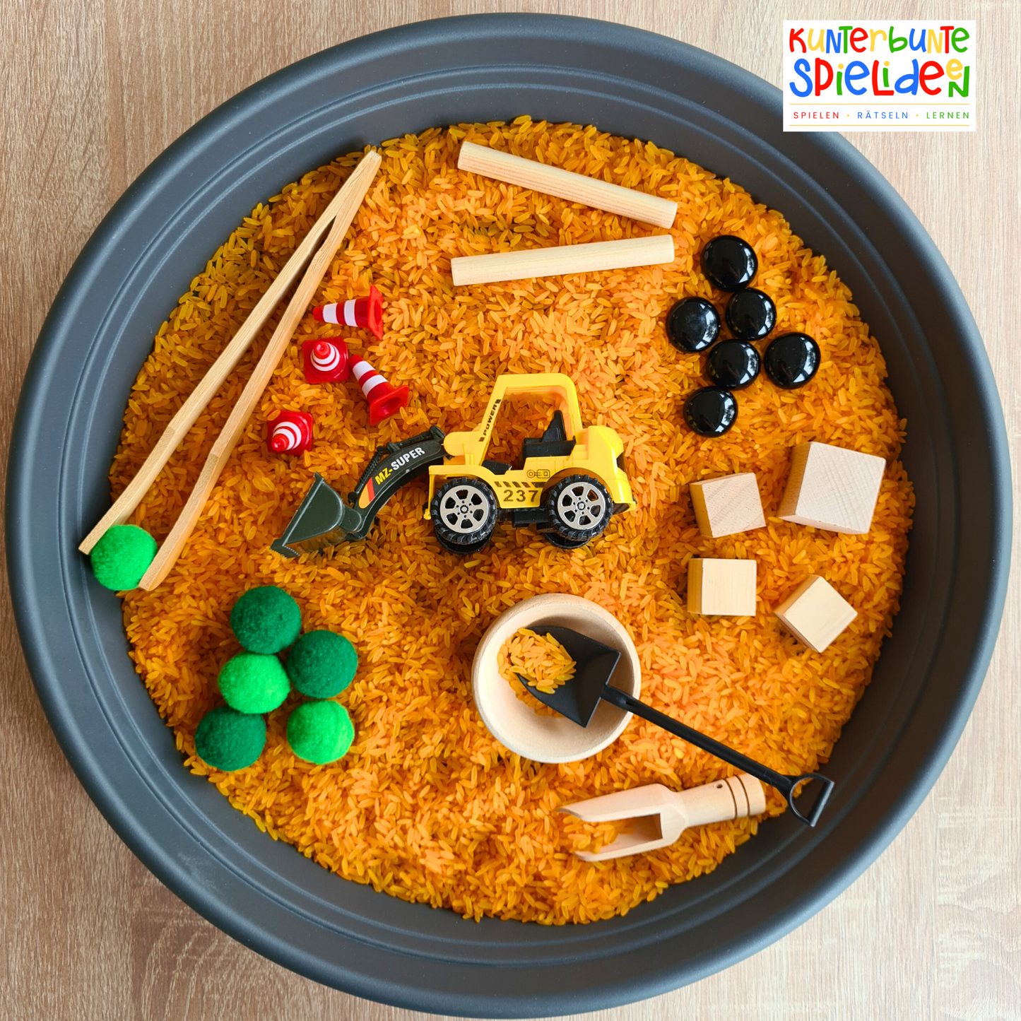 Sensorisches Spiel Baustelle mit gefärbtem Reis, Baustellenfahrzeugen, Schüttwerkzeugen und losen Materialien. Montessori Sinnesspiel für Kinder mit Schüttspielen, Sensory Play und Sinnesförderung zur Förderung von Feinmotorik, Konzentration und kreativem Entdecken.
