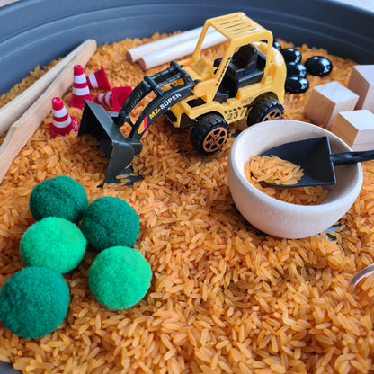 Montessori Sinnesspiel Baustelle mit sensorischem Reis, Baustellenfahrzeug, Schüttwerkzeugen und losen Materialien für Schüttspiele und Sensory Play. Sensorisches Spiel für Kinder zur Förderung von Feinmotorik, Konzentration, Sinnesförderung und kreativem Entdecken.