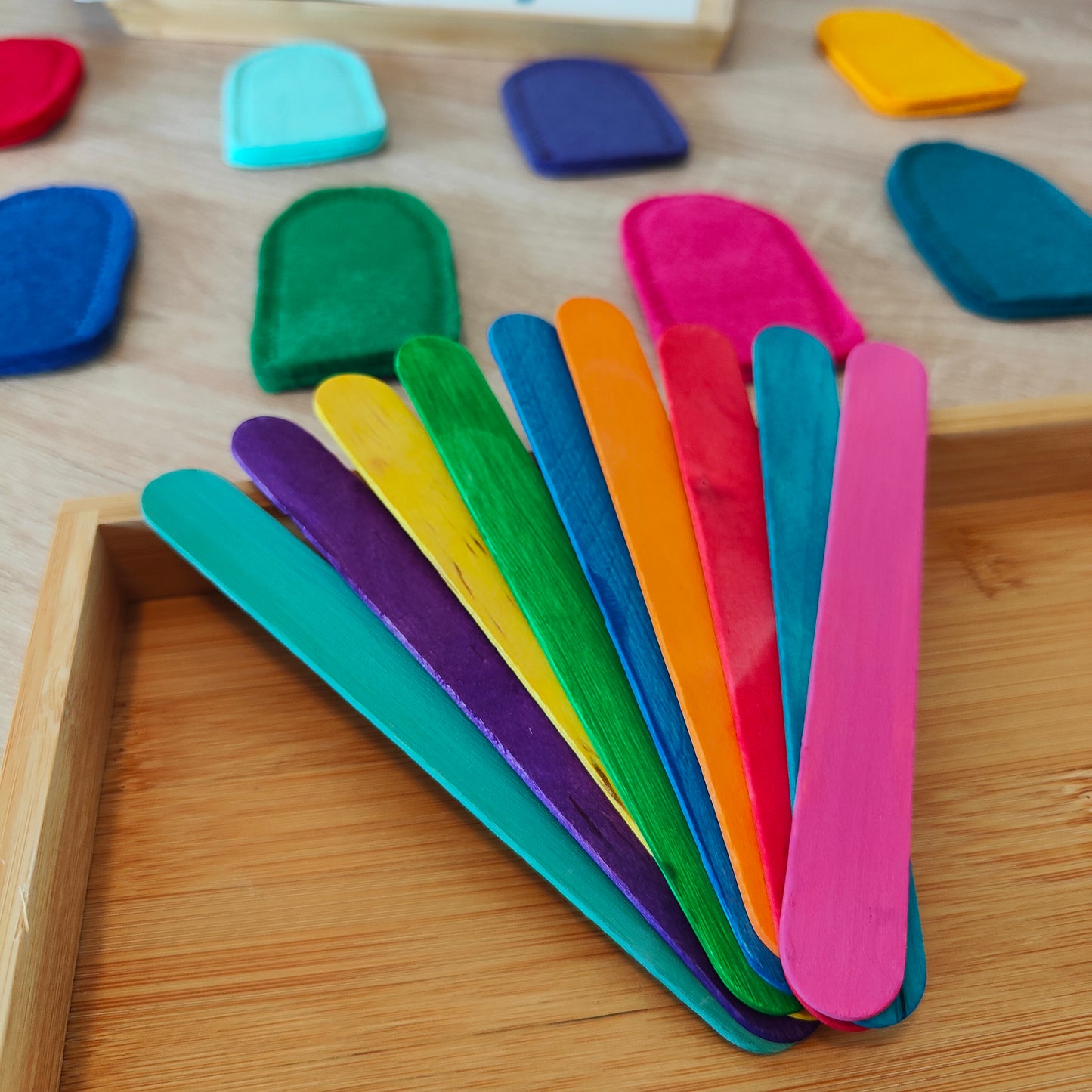 Kindgerechtes Steckspiel für Kinder ab 3 Jahren, bei dem farbige Holzstäbchen mit passenden Filzeiskugeln kombiniert werden, um Farben zu lernen und die Feinmotorik zu fördern
